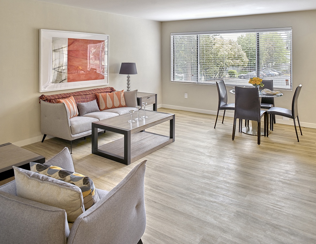 a living and dining room area with a couch table and chairs and a large window